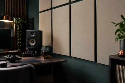 Panneaux acoustiques beige en polyester fixés au mur d’un home-studio rangé avec bureau en bois sombre